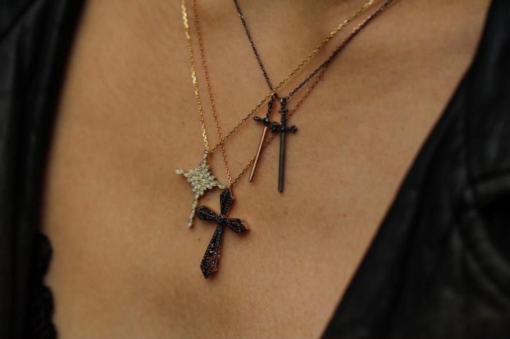 Collier Jaeger aux dagues croisées porté en superposition sous un blouson de cuir